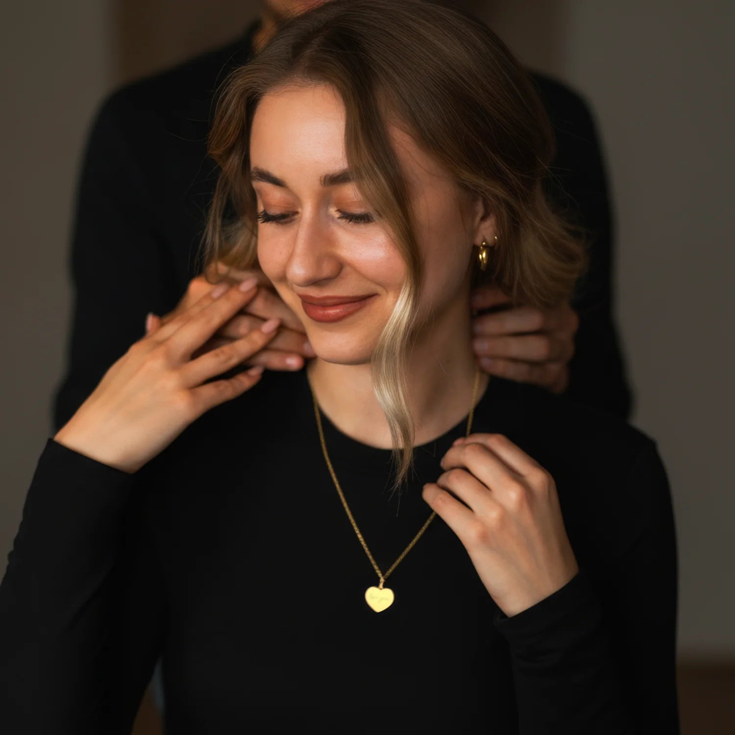 Frau trägt eine Herzkette mit individueller Gravur aus Symbol, Initialen oder Datum und persönlicher Widmung